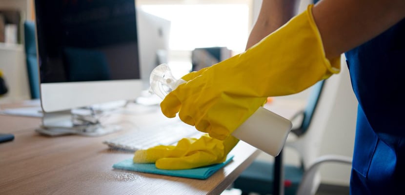 Persona experimentada limpiando escritorio con productos de limpieza especializados