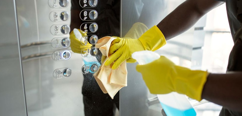 Profesional del aseo limpia con productos especiales de limpieza el interior de un ascensor
