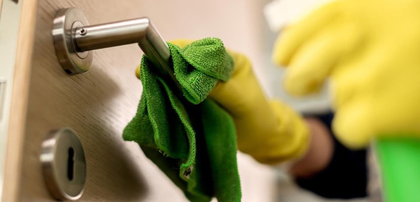 Profesional de limpieza limpia la chapa de una puerta