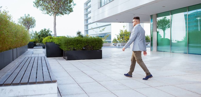 Hombre de negocios camina por un espacio al aire libre de un parque empresarial