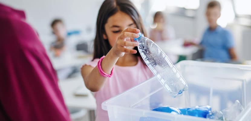 Niña depositando un recipiente vacio en una caneca entendiendo que son los residuos ordinarios y no reciclables explicado por Misión Servir