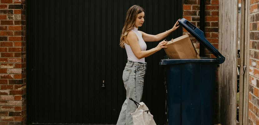 Mujer sacando la basura en lugar destinado para recolección de residuos mostrando las normas para shut de basuras en Colombia